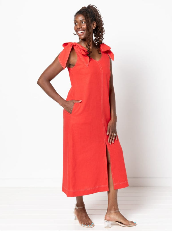 Woman wearing a red dress made using a style arc Esther woven dress sewing pattern with bow shoulders on a white background