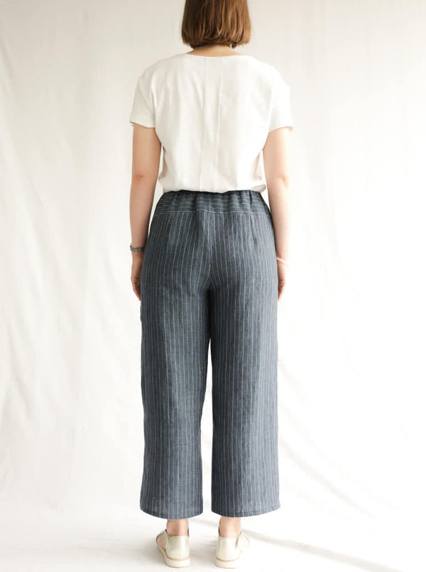 back view of lady wearing blue stripped linen pant made using Fifi Woven Pant sewing pattern, featuring a wide leg design with a smooth front yoke, elastic back, and side pockets, perfect for crepe, linen, and rayon fabrics.