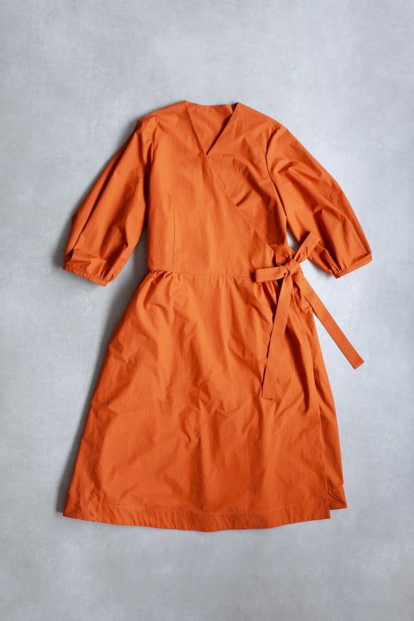 OrangeWrap Dress made with PDF sewing patternwith long sleeves and a belt on a gray background