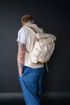Person wearing a white backpack against a dark background