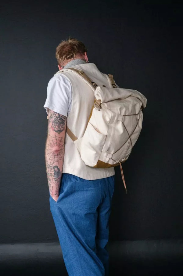 Person wearing a white backpack against a dark background