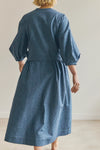 Person wearing a blue malie Wrap Dress made with PDF sewing pattern with puffed sleeves against a plain background