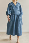 Woman wearing a blue malie Wrap Dress made with PDF sewing patternagainst a plain background