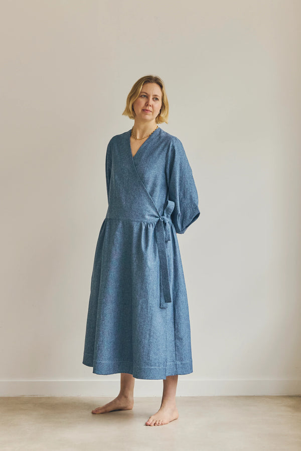 Woman wearing a blue malie Wrap Dress made with PDF sewing pattern against a plain background