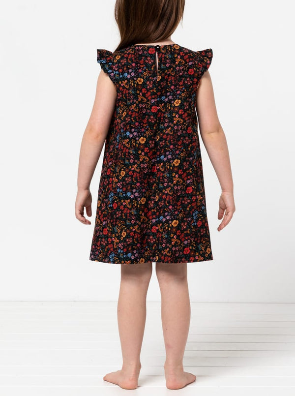 Child wearing a floral dress made using andie kids dress sewing pattern on a white background