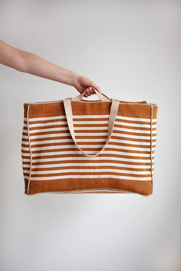 Striped tote bag with a hand made using the Away Tote PDF Sewing Patternholding it against a plain background