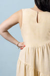 Beige dress made using Azure Dress, Skirt, and Top sewing pattern worn by a person against a light blue background