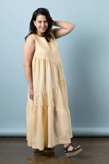 Woman wearing a beige sleeveless dress made using Azure Dress, Skirt, and Top sewing pattern against a light blue background