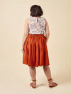 Woman wearing a floral top and rust-colored skirt made using Azure Dress, Skirt, and Top sewing pattern on a beige background