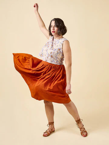 Woman wearing a floral top and orange skirt made using Azure Dress, Skirt, and Top sewing pattern on a beige background
