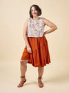 Woman wearing a sleeveless floral top and rust-colored skirt made using Azure Dress, Skirt, and Top sewing pattern on a beige background