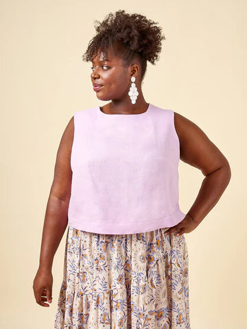 Woman wearing a light purple sleeveless top and floral skirt made using Azure Dress, Skirt, and Top sewing pattern on a beige background