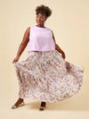 Woman wearing a light purple sleeveless top and floral skirt on a beige background