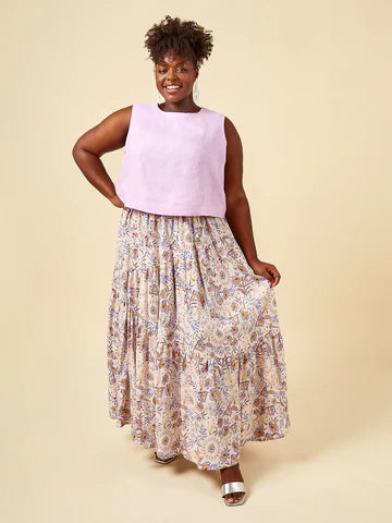 Woman wearing a light purple sleeveless top and floral skirt on a beige background