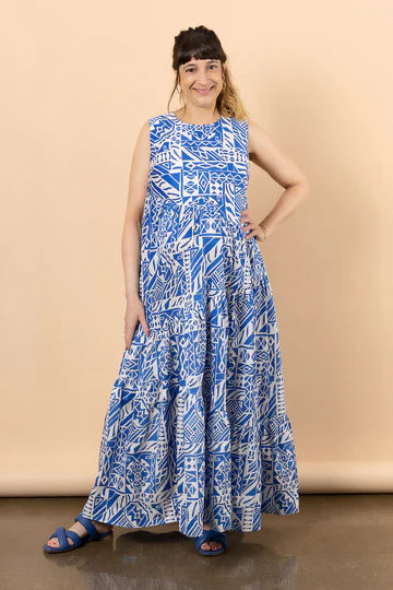 Woman wearing a blue and white patterned dress made using Azure Dress, Skirt, and Top sewing pattern against a beige background