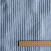 Bluehaven Pinstripe linen fabric in pale blue with fine navy pinstripes, 100% linen, 140 GSM, 60 LEA yarn dyed with a wooden ruler for scale