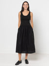 Woman wearing a black sleevelessCarter Dress made using StyleArc pattern with tee bodice and mid-calf linen skirt on a white background