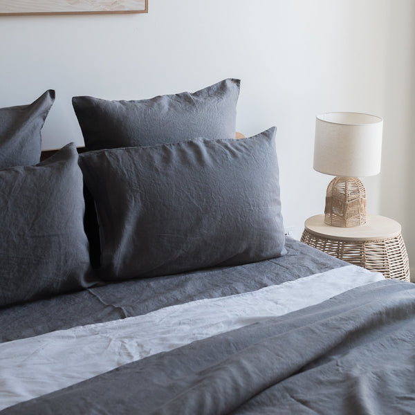 Greypillowcasesset on a bed with a lamp and side table in the background.