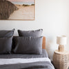 Bedroom with Charcoal grey linen pillowcasesand a lamp on a side table.