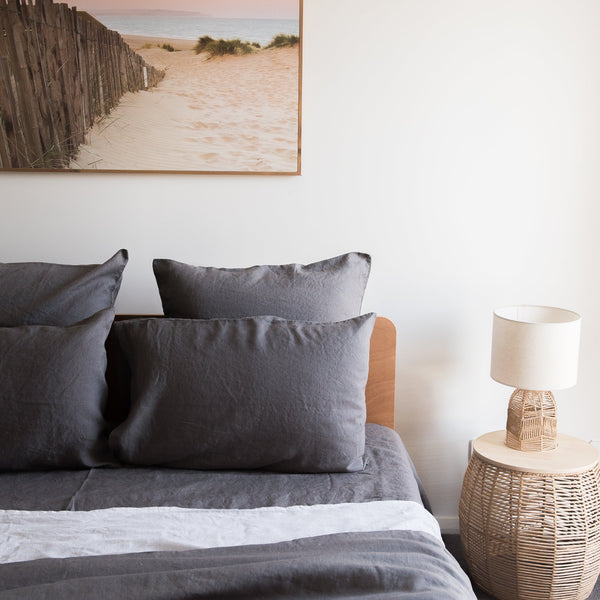 Bedroom with Charcoal grey linen pillowcasesand a lamp on a side table.