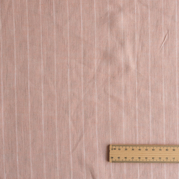 Pink fabric with subtle striped pattern and a wooden ruler for scale on a matching background