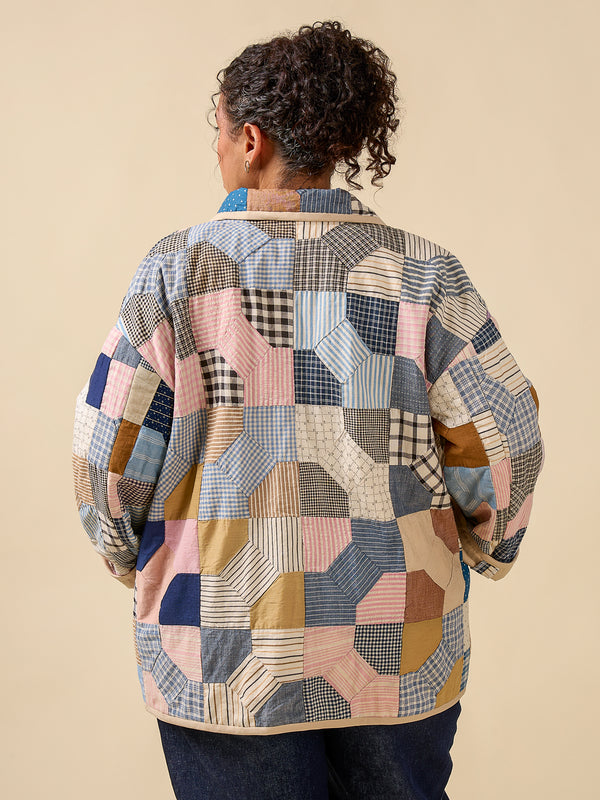 Person wearing a patchwork jacket with a beige background