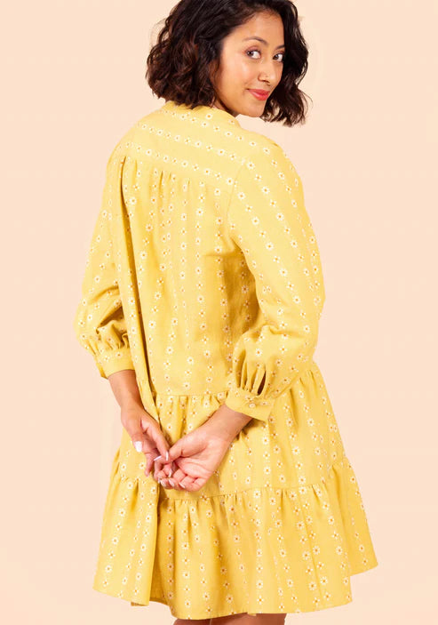 Woman wearing a yellow Poppy Dress with a subtle pattern on a beige background