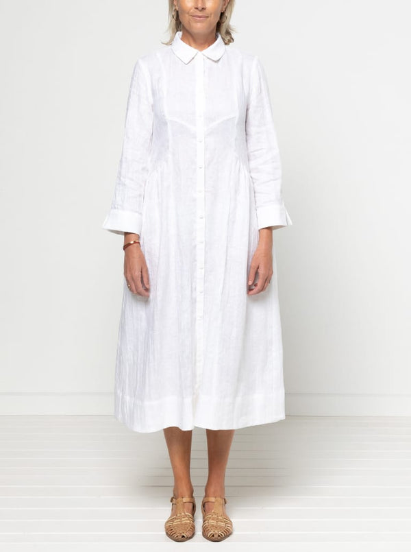 Person wearing a white dress against a plain background. The dress is made from the Hampton Woven Dress Sewing Pattern – a mid-calf shirtdress with a gathered skirt, curved waist, sleeve or sleeveless options, and inseam pockets.