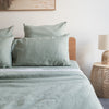 Bed with green bedding and Harbour Sage linen pillowcasesin a bedroom setting.