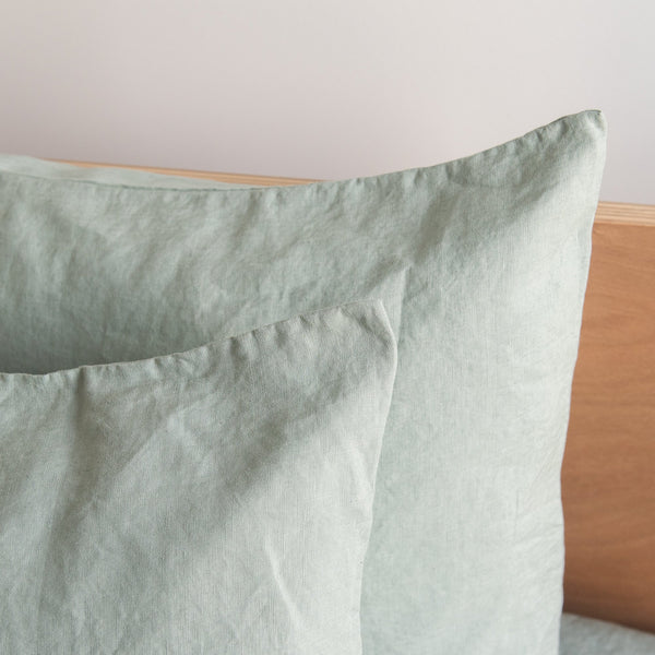 Harbour Sage linen pillowcaseson a wooden headboard
