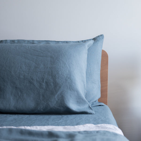 Lake blue linen pillowcases and bedding on a bed with a blurred background
