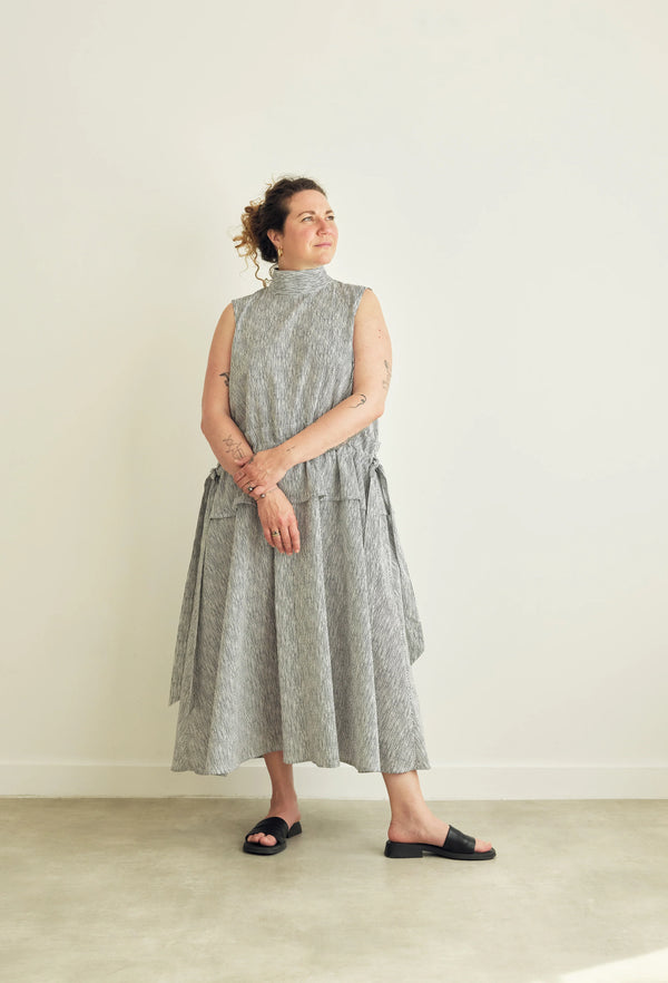 Woman wearing a sleeveless, patterned dress against a plain background