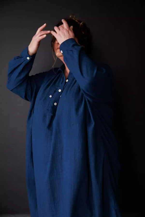 Person wearing a blue long-sleeve garment against a dark background