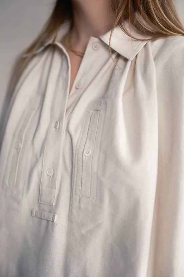 Close-up of a person wearing a light-colored shirt with a neutral background