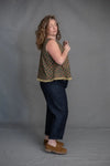 Woman wearing a patterned top and dark pants made using The Eve Trouser Sewing Pattern by Merchant & Mills – cropped tapered trousers with side zip and pleats against a plain background