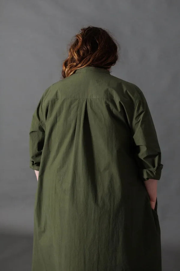 Person wearing a green dress made using The Niven Sewing Pattern by Merchant & Mills against a gray background