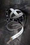Merchant & Mills black and white tailor’s tape measure with 150cm and 60-inch markings, made in Germany coiled on a dark surface