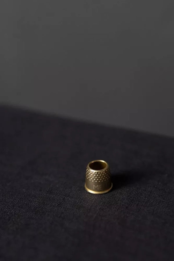Small brass thimble on a dark textured surface