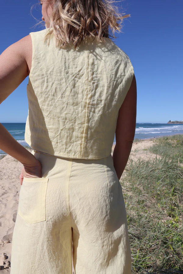 Pipit Vest Sewing Pattern - Reversible Oversized Vest in Two Lengths. Image of A woman wearing pipit vest made of yellow colour linen fabric in the beach side