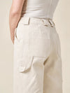 Beige pantsmade of Rika Pants sewing pattern in cropped tailored style with hem cuffs and tabbed waistbandworn by a person on a beige background