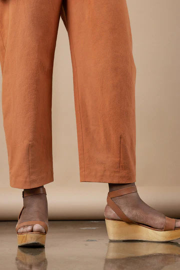 Brown pants made using Sepia Pants and Shorts sewing patternand sandals on a neutral background