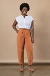 Woman wearing a white blouse and orange pants made using Sepia Pants and Shorts sewing pattern against a beige background