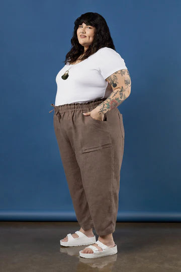Woman wearing a white t-shirt and brown pants made using Sepia Pants and Shorts sewing patternagainst a blue background