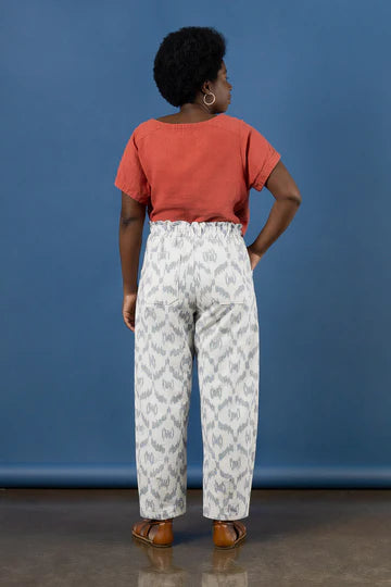 Person wearing a red top and white patterned pants made using Sepia Pants and Shorts sewing pattern against a blue background