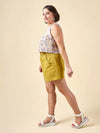Woman wearing a floral top and yellow shorts made using Sepia Pants and Shorts sewing pattern on a beige background