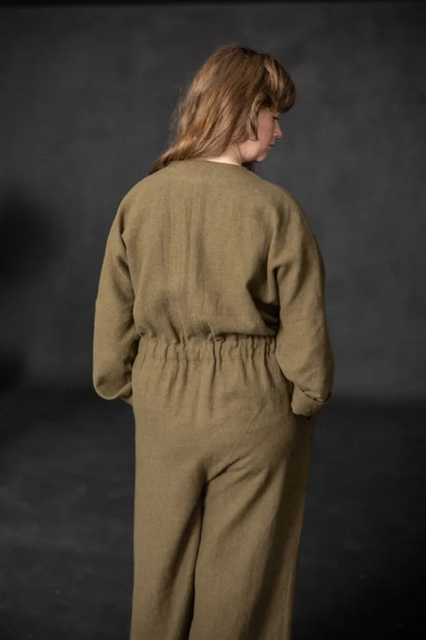 Person wearing a brown cassidy jumpsuit against a dark background