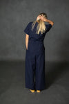 Person wearing a navy bluecassidy jumpsuit against a dark gray background