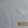 Textured Whisper Moss Stripe linen–organic cotton fabric with thin eucalyptus green stripes on white, 140 GSM. with a ruler for scale on a matching background