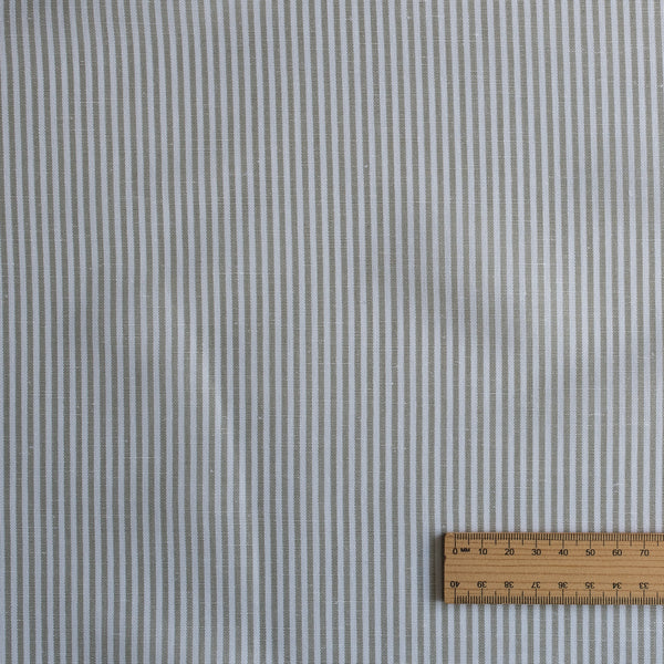 Textured Whisper Moss Stripe linen–organic cotton fabric with thin eucalyptus green stripes on white, 140 GSM. with a ruler for scale on a matching background