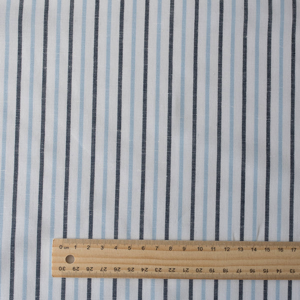 Alternating sky blue and midnight vertical stripes on a white linen blend fabric, with a natural slub texture and soft appearance.